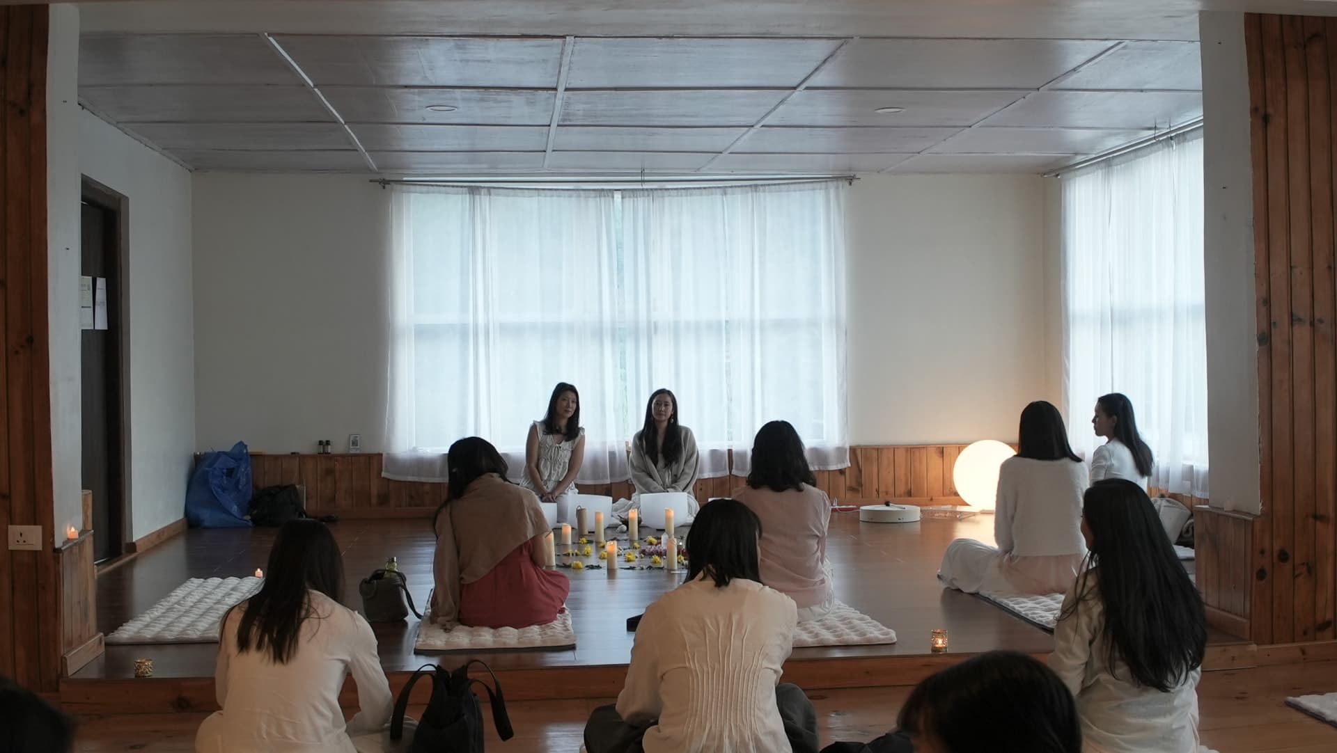 A candlelit circle gathered in white with Tshering and Jigme holding space