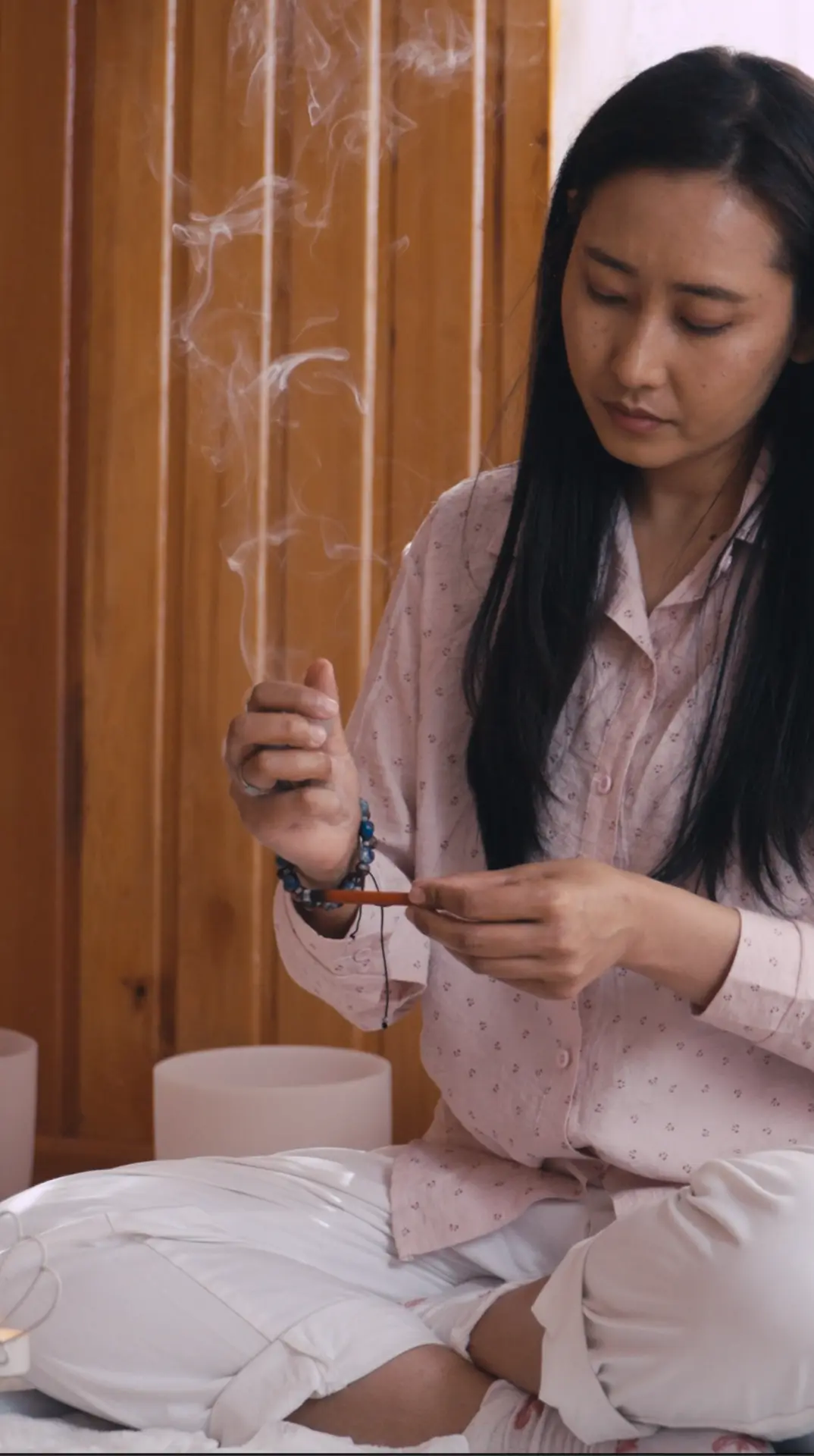 Tshering lighting incense beside crystal singing bowls