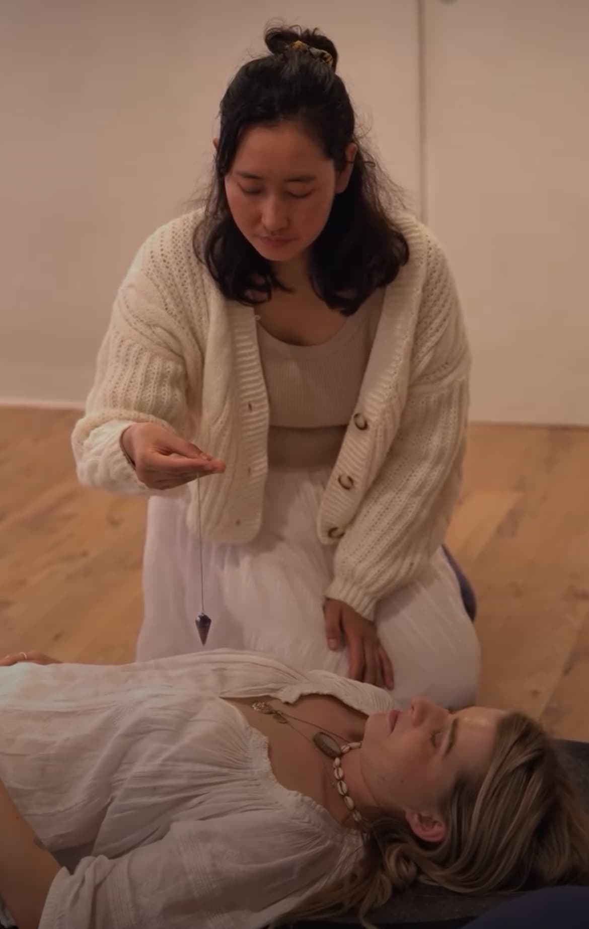 Tshering holding a pendulum over a resting client